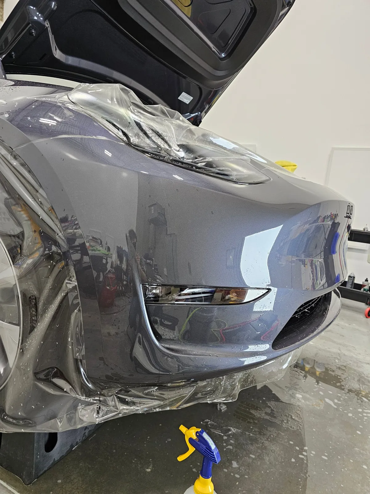 Grey Tesla Model Y with the frunk open during a front end PPF install.