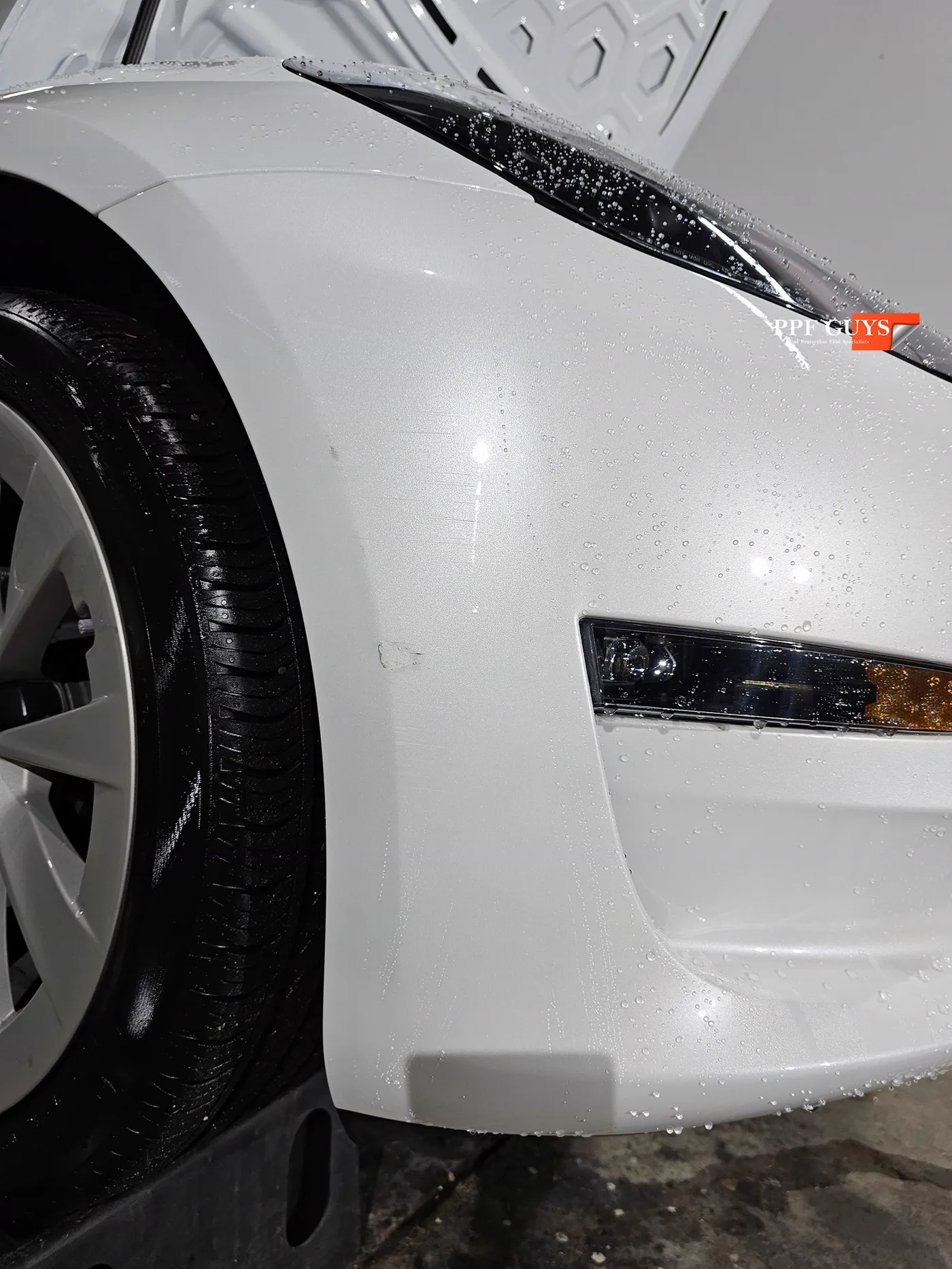 White Tesla Model 3 front bumper after scraping a concrete pillar.