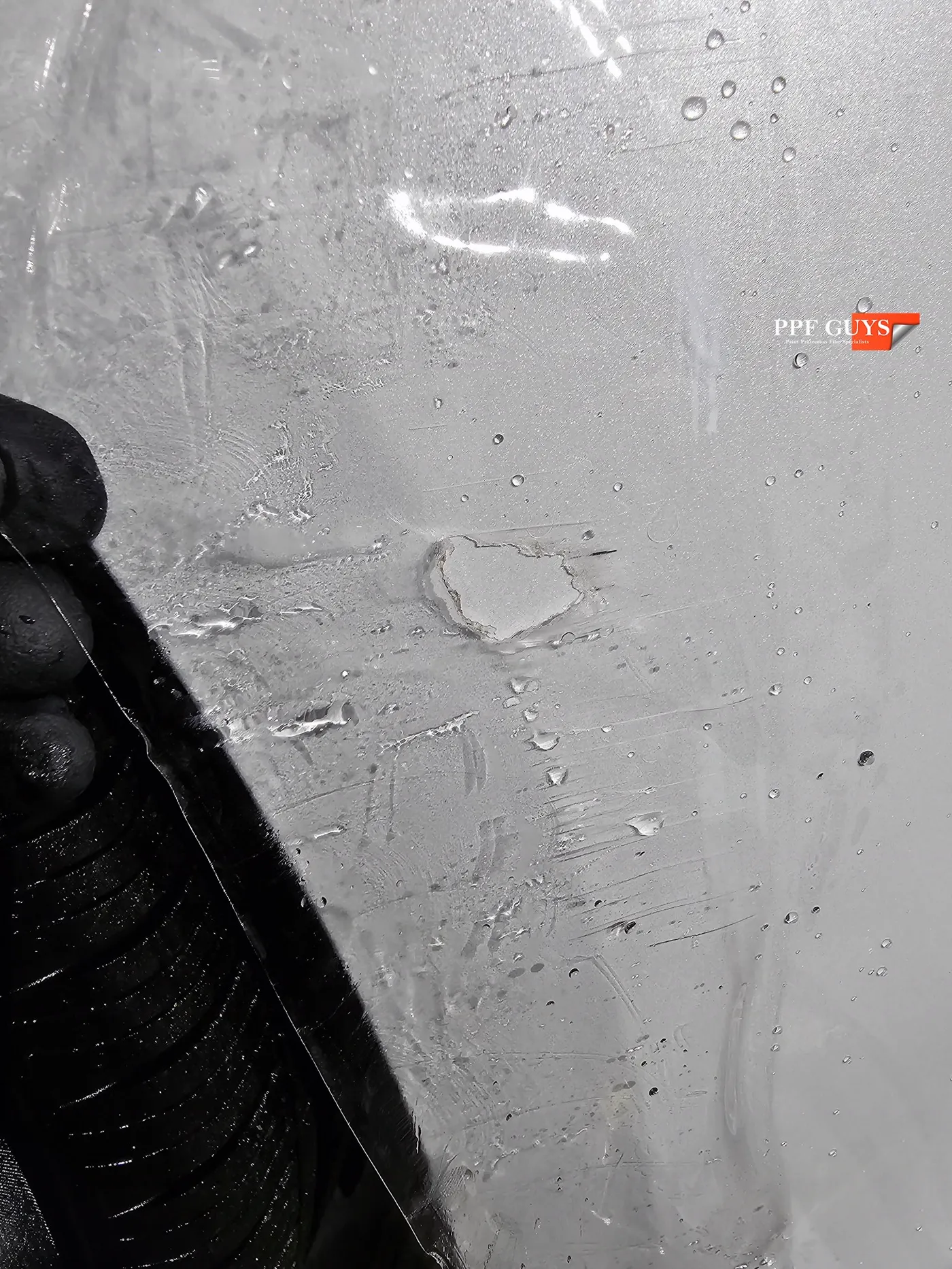 Damaged PPF being peeled away from the bumper.